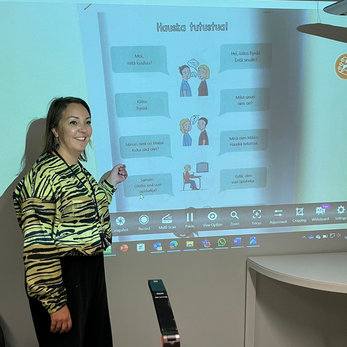 Nainen esittelee presentaatiota luokkahuoneen edessä